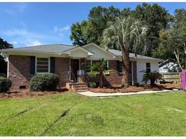 Charming brick home with a well-manicured lawn and mature landscaping, including palm trees at 2456 Lantern St, Charleston, SC 29414