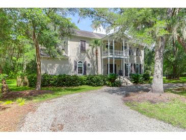 Charming two-story home with a gravel drive, lush landscaping, and a welcoming front porch at 2494 Cape Rd, Johns Island, SC 29455