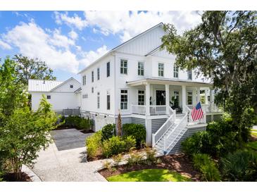 Beautiful two-story white home with an inviting front porch, lush landscaping, and a spacious driveway at 566 Wading Pl, Daniel Island, SC 29492