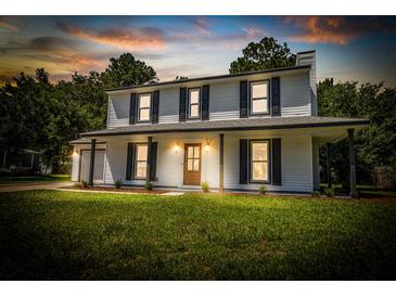 Charming two-story home featuring a covered front porch, dark shutters, and a lush green lawn at 107 Sugarpine Pl, Summerville, SC 29486