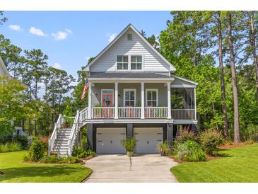 Charming two-story home featuring a welcoming front porch, two-car garage, and lush landscaping at 129 Martins Point Dr, Wando, SC 29492