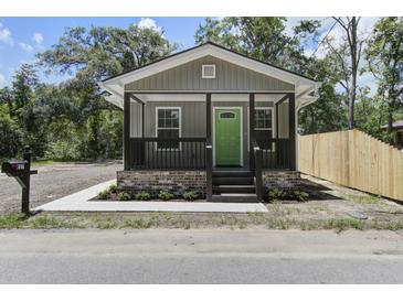 Charming home featuring a covered front porch with a bright green door and manicured landscaping at 227 Grace St, Walterboro, SC 29488