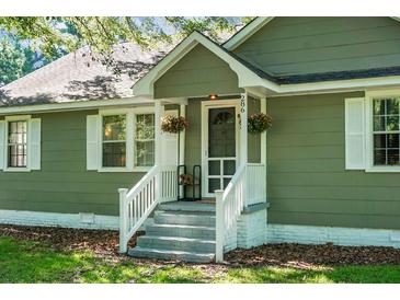 Charming home featuring a welcoming front entrance with hanging flower baskets and a cozy chair on the porch at 286 Mallard Lake Rd, Dorchester, SC 29437