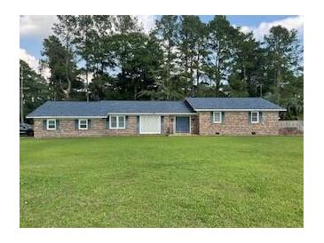 Charming brick home featuring a well-manicured lawn and complemented by mature trees at 306 Park St, Saint George, SC 29477