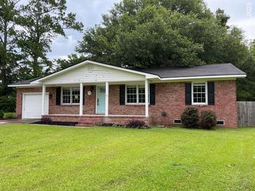 Charming one-story red brick home with a well-manicured lawn, a light blue door and black shutters at 352 Oxford Rd, Ladson, SC 29456