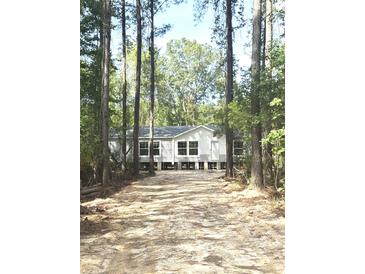 Charming single-story home with white siding and dark trim surrounded by tall trees at 144 Craft Ln, Round O, SC 29474