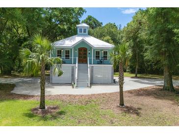 Charming coastal home featuring a light blue exterior, white trim, elevated design, and lush landscaping with palm trees at 16 Oakwood Ln, Edisto Island, SC 29438