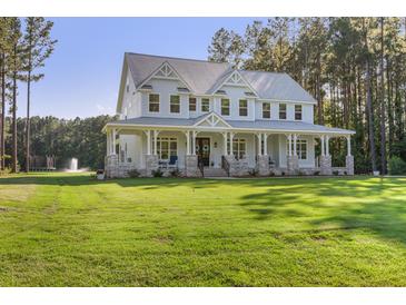 Stunning two-story home with a sprawling porch, lush lawn, and mature trees, offering curb appeal and outdoor space at 1130 Plantation Overlook Dr, Moncks Corner, SC 29461