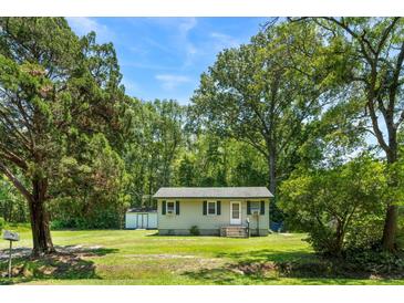 Charming single-story home with a lush green lawn and mature trees, creating a serene and inviting curb appeal at 1879 Richmond St, Charleston, SC 29407