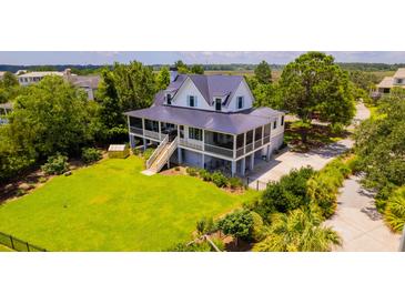 Beautiful two-story home with lush green lawn, screened in porches, and large wooden staircase at 2312 Rushland Landing Rd, Johns Island, SC 29455