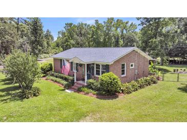 Charming brick home with well-maintained lawn, pretty shrubbery, and an American flag waving at 7274 Commodore Rd, Hollywood, SC 29449