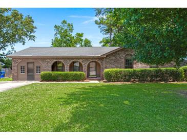 Charming single-story brick home with arched entryway, lush green lawn, and well-maintained landscaping at 8116 Long Shadow Ln, North Charleston, SC 29406