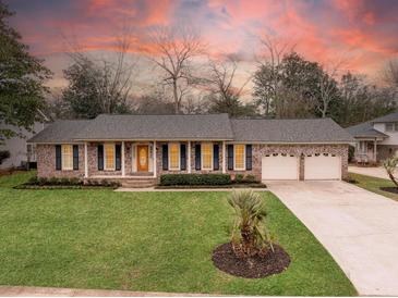Brick house with a well-manicured lawn, mature trees, and a two-car garage, providing excellent curb appeal at 1043 Dominion Dr, Hanahan, SC 29410