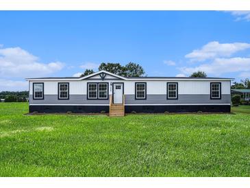 Charming manufactured home showcasing a well-manicured lawn and classic architectural details at 1326 Givhans Rd, Ridgeville, SC 29472