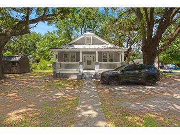 Charming gray cottage-style home with a quaint front porch and mature trees at 2170 Midland Park Rd, North Charleston, SC 29406