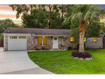Charming brick home featuring a well-manicured lawn, palm tree, and inviting front porch with seating at 1990 Butternut St, Charleston, SC 29414