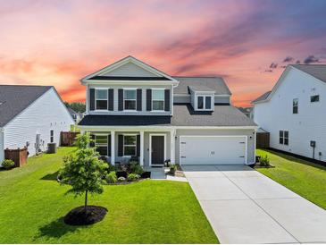 Inviting two-story home featuring a manicured lawn and attached two-car garage at 291 Lucca Dr, Summerville, SC 29486