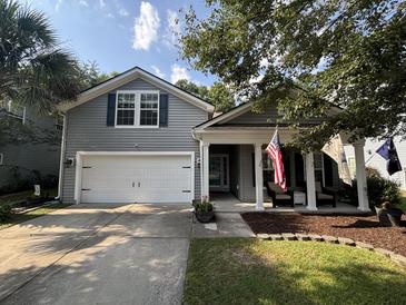Charming two-story home with gray siding, a two-car garage, and a welcoming front porch with American flags at 5008 W W Liberty Meadows Dr, Summerville, SC 29485