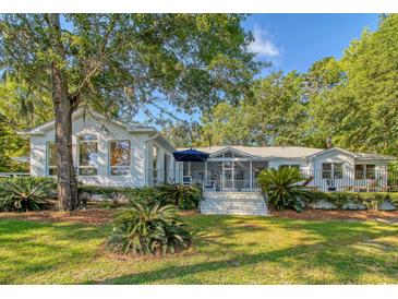 Expansive, single-story home with lush landscaping and a screened-in porch, perfect for outdoor relaxation at 5084 Timber Race Crse, Hollywood, SC 29449