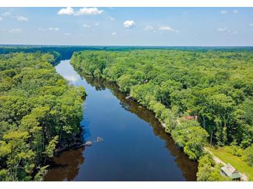 Overhead shot of dark river winding through lush green trees with a bright blue sky overhead at 150 Riverbend Ln, Ridgeville, SC 29472