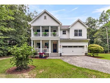 Charming two-story white home featuring a double porch, attached garage, and a well-maintained lawn at 2226 Arthur Rose Ln, Johns Island, SC 29455