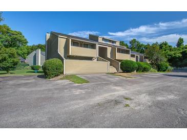 Inviting exterior of a multi-story tan home with landscaped bushes and nearby trees under a bright, sunny, blue sky at 2334 Treescape Dr # 2006, Charleston, SC 29414