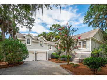 Charming home featuring a two-car garage, complemented by lush landscaping and beautiful crape myrtle trees at 2645 Gnarled Pine, Seabrook Island, SC 29455
