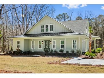 Charming exterior view of a single-story home with a metal roof, inviting front porch, and meticulously landscaped front yard at 2725 Starfish Dr, Johns Island, SC 29455