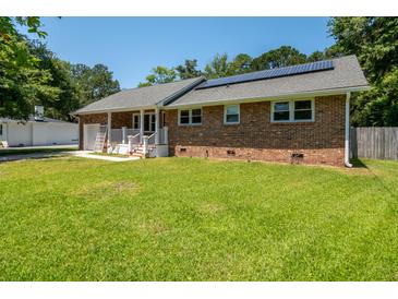 Charming brick home featuring solar panels, a well-maintained lawn, and a welcoming garage at 327 Mcclain St, Charleston, SC 29407