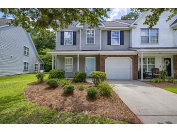 Charming two-story townhouse featuring a light blue front door, white garage door, and well-manicured landscaping at 8721 Grassy Oak Trl, North Charleston, SC 29420