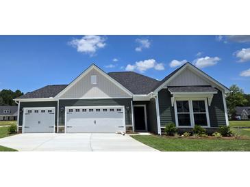 Charming single-story home with a two-car garage and well-maintained landscaping under a blue sky at 111 Captains Creek Ln, Ridgeville, SC 29472