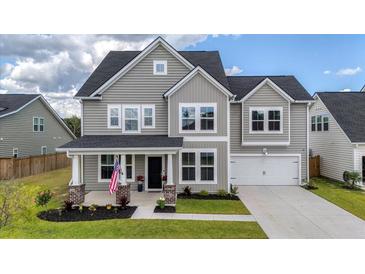 Charming two-story home with gray siding, front porch, manicured lawn, and a two-car garage at 1115 Fitzgerald Ct, Summerville, SC 29485