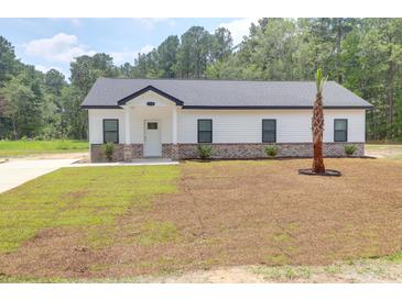 Charming single-story home features white siding, brick accents, and a freshly landscaped yard with a palm tree at 112 Southsong Ln, Goose Creek, SC 29445