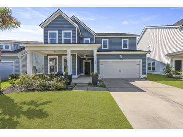 Charming two-story home with blue siding, a two-car garage, and a welcoming front porch with seating at 120 Haverhill St, Summerville, SC 29486