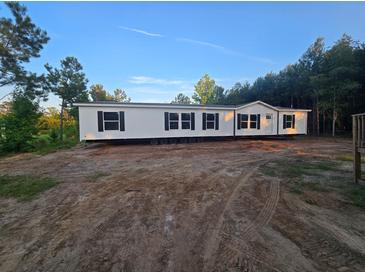 New manufactured home with dark shutters on a spacious lot surrounded by mature trees under clear skies at 1420 Rehoboth Rd, Cottageville, SC 29435