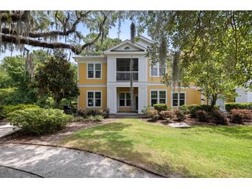 Inviting yellow two-story home with a screened porch, surrounded by lush landscaping and mature trees at 1915 Chatelain Way, Mount Pleasant, SC 29464