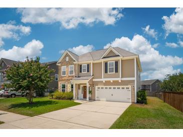 Charming two-story home featuring a well-manicured lawn, attached garage and a mix of brick and vinyl siding at 3274 Arrow Arum Dr, Johns Island, SC 29455