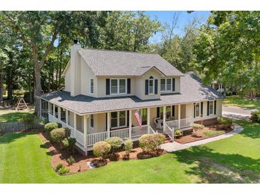 Charming two-story home featuring a spacious porch, manicured lawn, and beautiful landscaping at 207 Littlejohn St, Summerville, SC 29483