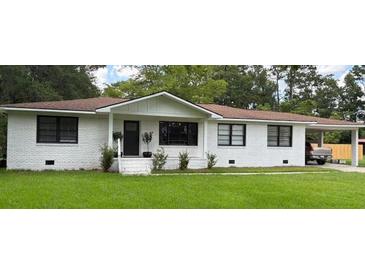 Charming one-story home with white brick exterior, well-manicured lawn, and covered carport at 702 N N Palmetto St, Summerville, SC 29483