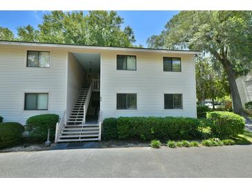 Two-story condo building with open stairwell, neutral siding, and manicured landscaping at 93 Ashley Hall Plantation Rd # 6, Charleston, SC 29407
