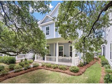 Charming blue two-story home featuring a cozy front porch and beautifully landscaped yard at 1052 Avenue Of Oaks, Charleston, SC 29407