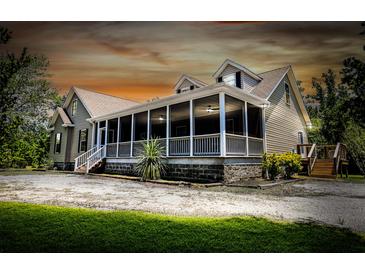 Charming home featuring a spacious screened-in porch with ceiling fans and a well-manicured yard at 153 Willow Brook Way, Cordesville, SC 29434