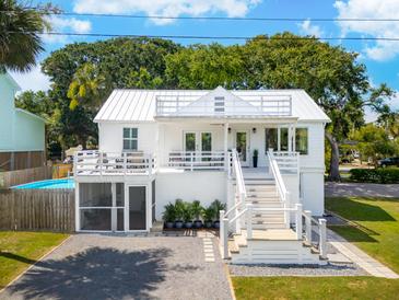 Charming two-story white home with a spacious deck and a screened-in porch at 2407 Cameron Blvd, Isle of Palms, SC 29451