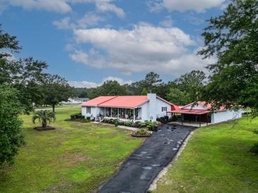 Charming single-story home boasts a red roof, a well-manicured lawn, and a long asphalt driveway at 274 Harvest Rd, Moncks Corner, SC 29461