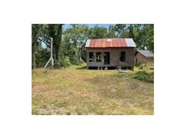 Exterior home view showing a small structure with a rusted metal roof and a large yard at 305 E 1St N St, Summerville, SC 29483