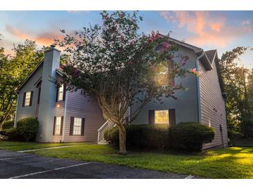 Charming condo featuring mature landscaping, a chimney, and beautiful sunset lighting at 7950 Parklane Ct # C, North Charleston, SC 29418