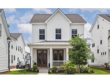 Charming two-story home featuring a welcoming front porch, well-manicured lawn, and classic white siding at 1244 Crooked Oak Rd, Charleston, SC 29492