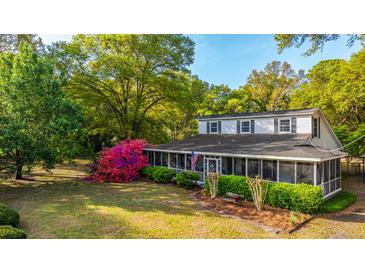 Charming two-story home featuring a screened porch, complemented by vibrant azaleas and lush landscaping at 1518 Southwick Dr, Johns Island, SC 29455