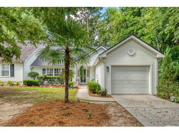 Charming one-story home with an attached garage and beautifully landscaped front yard with a palm tree at 9117 Woodcreek Ct, North Charleston, SC 29406