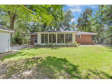 Expansive backyard featuring lush green lawn, mature trees, and a brick home with a wall of windows at 112 Roselle Ave, Goose Creek, SC 29445